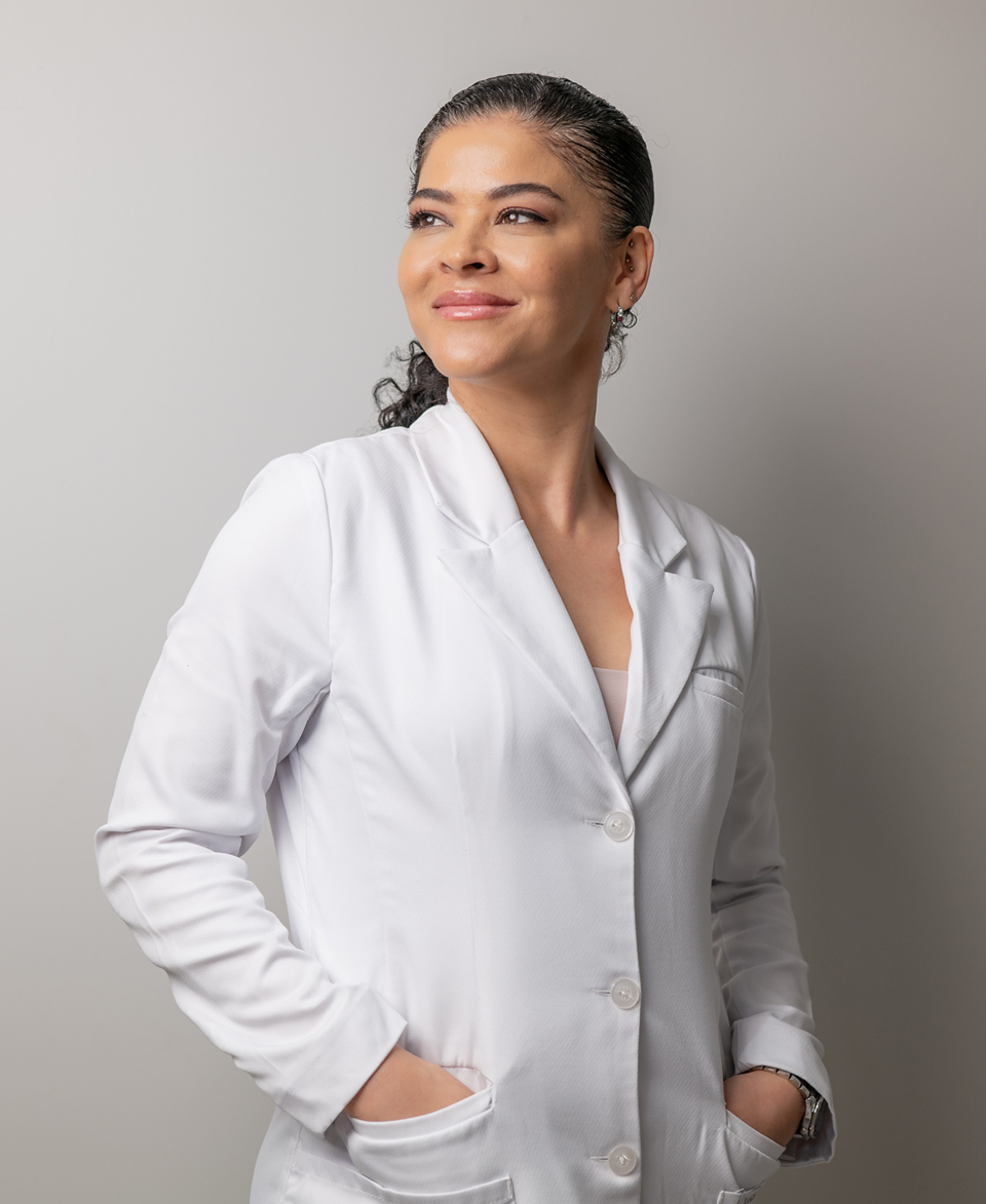 Dr Hilla in a white lab coat. She is smiling and looking to her right.